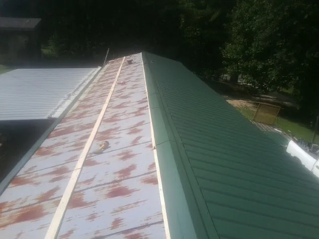 Old rusted panels beside newly installed green metal roofing — Wind Damage Roof Repair by Roofing Brothers in Cascadia