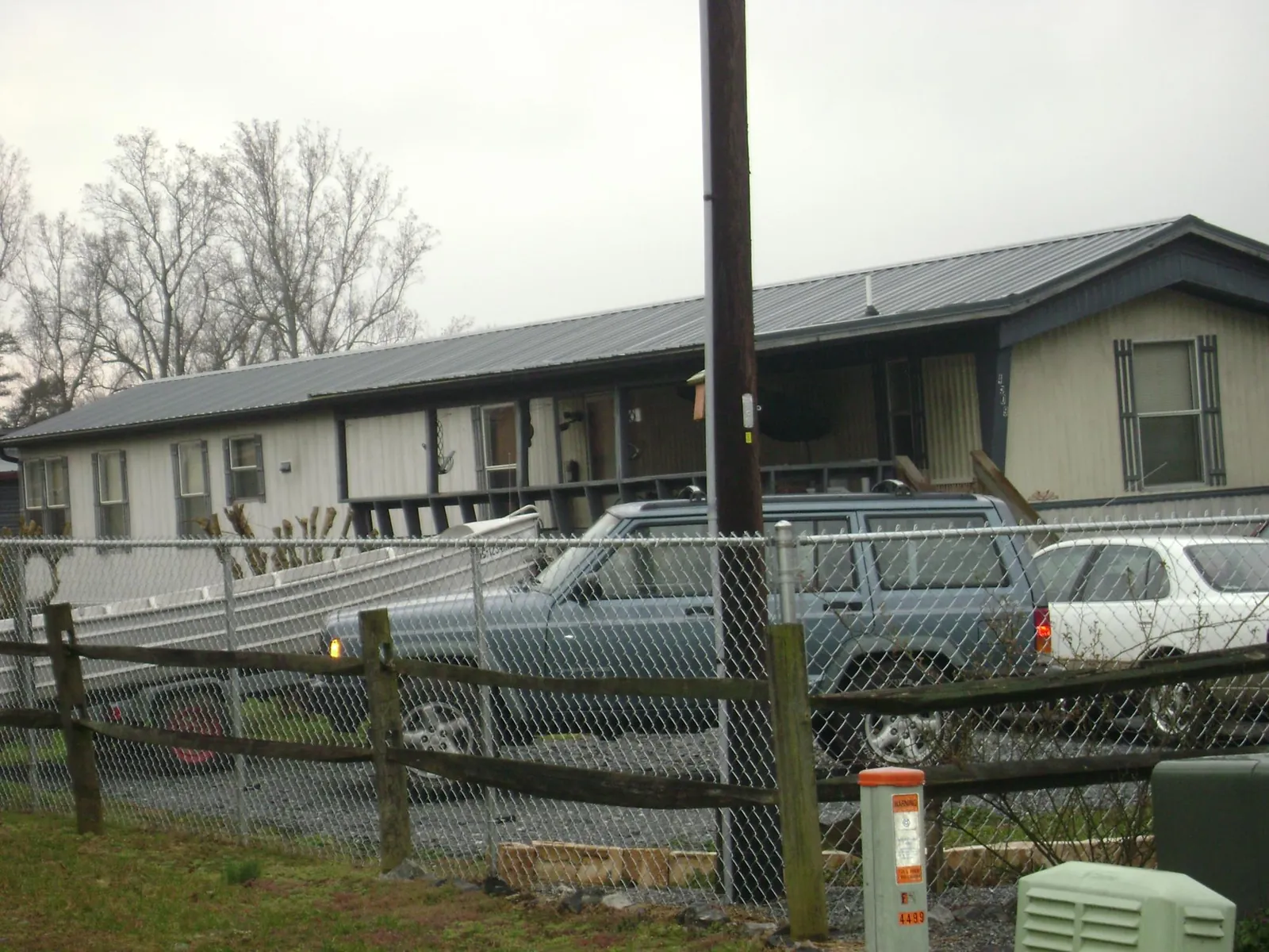 Dark metal roof on a long single story building behind a chain link fence in Cascadia