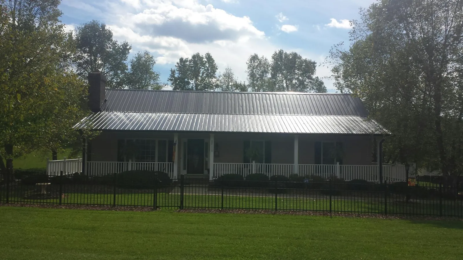 Gray metal roof on a brick ranch with a full width front porch — Gutter Guard Installation work by our crew in Cascadia