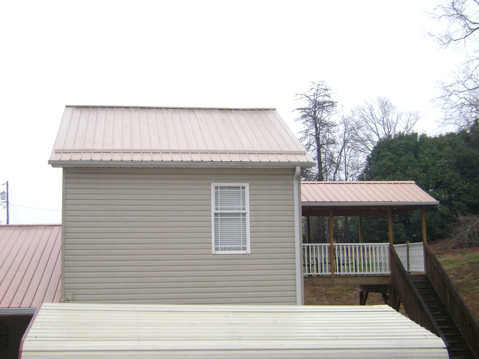 Tan metal roofs on a two story addition and attached porch, from a Roof Replacement job in Cascadia